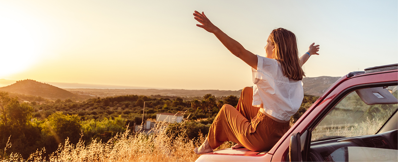 A joyful young woman is appreciating a beautiful summer sunset, embodying the vitality of life.