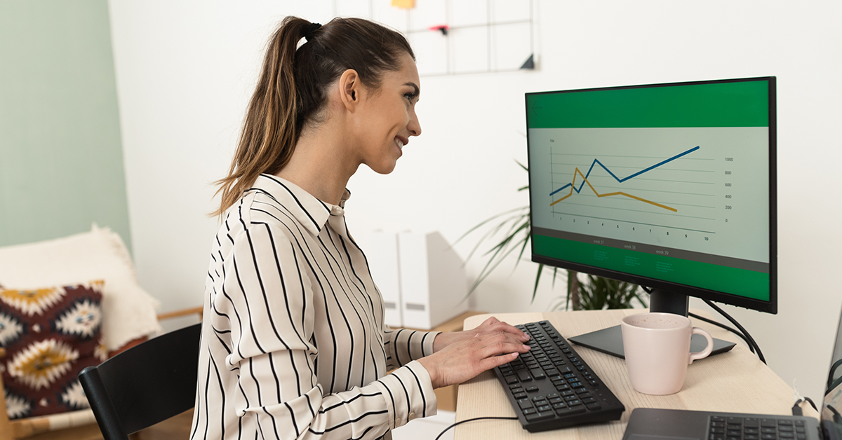 woman sitting at a desk in front of a computer looking at a chart