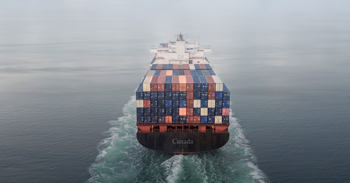 Image d'un porte-conteneurs avançant sur la mer, entrant dans une nappe de brouillard.