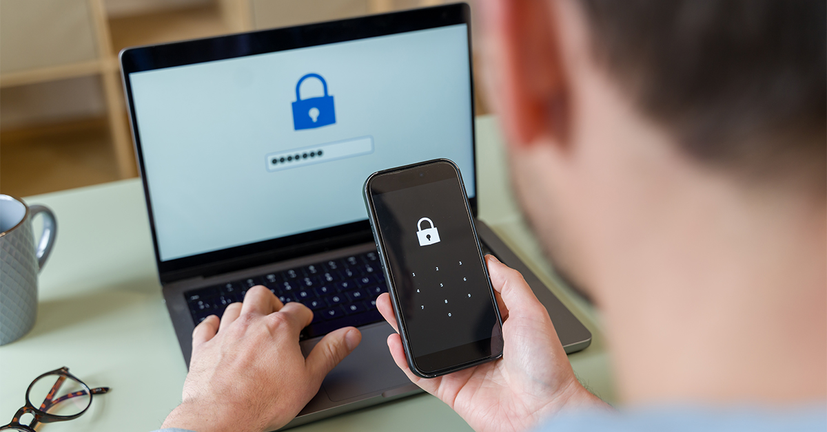 Person using two-factor authentication on a phone while typing a password on a laptop.