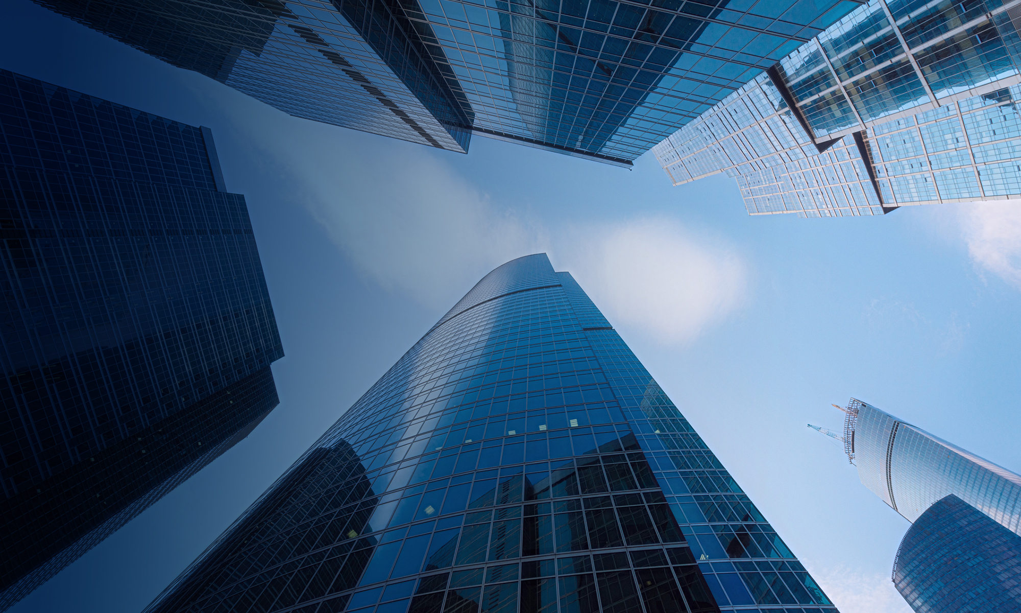 Modern skyscraper with sleek glass architecture reflects the blue sky, symbolizing innovation in urban business design.