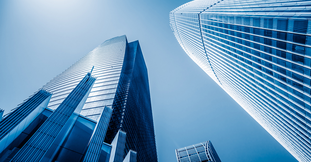 A modern glass skyscraper reflects the blue sky, showcasing sleek architecture in a bustling city business district.