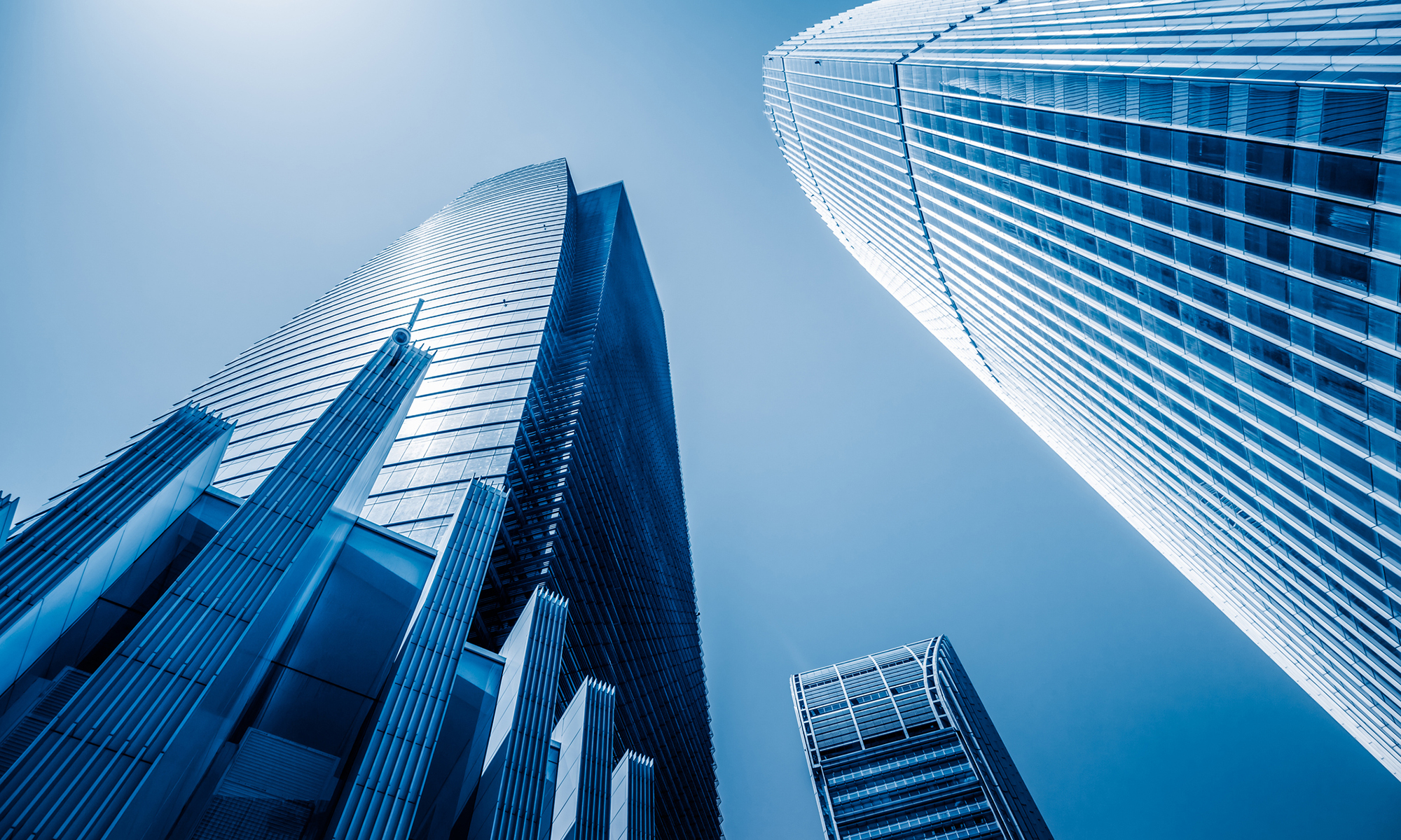 A modern glass skyscraper reflects the blue sky, showcasing innovative architecture in a bustling business district.
