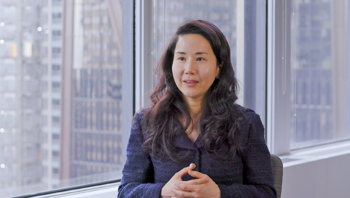 Landscape corporate headshot of a woman, solo, facing forward during a client presentation; professional, composed.