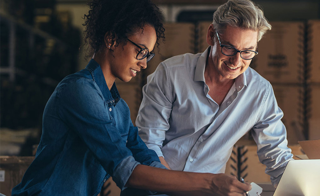 A smiling couple sits together in a professional setting, portraying a balance of business focus and family connection.