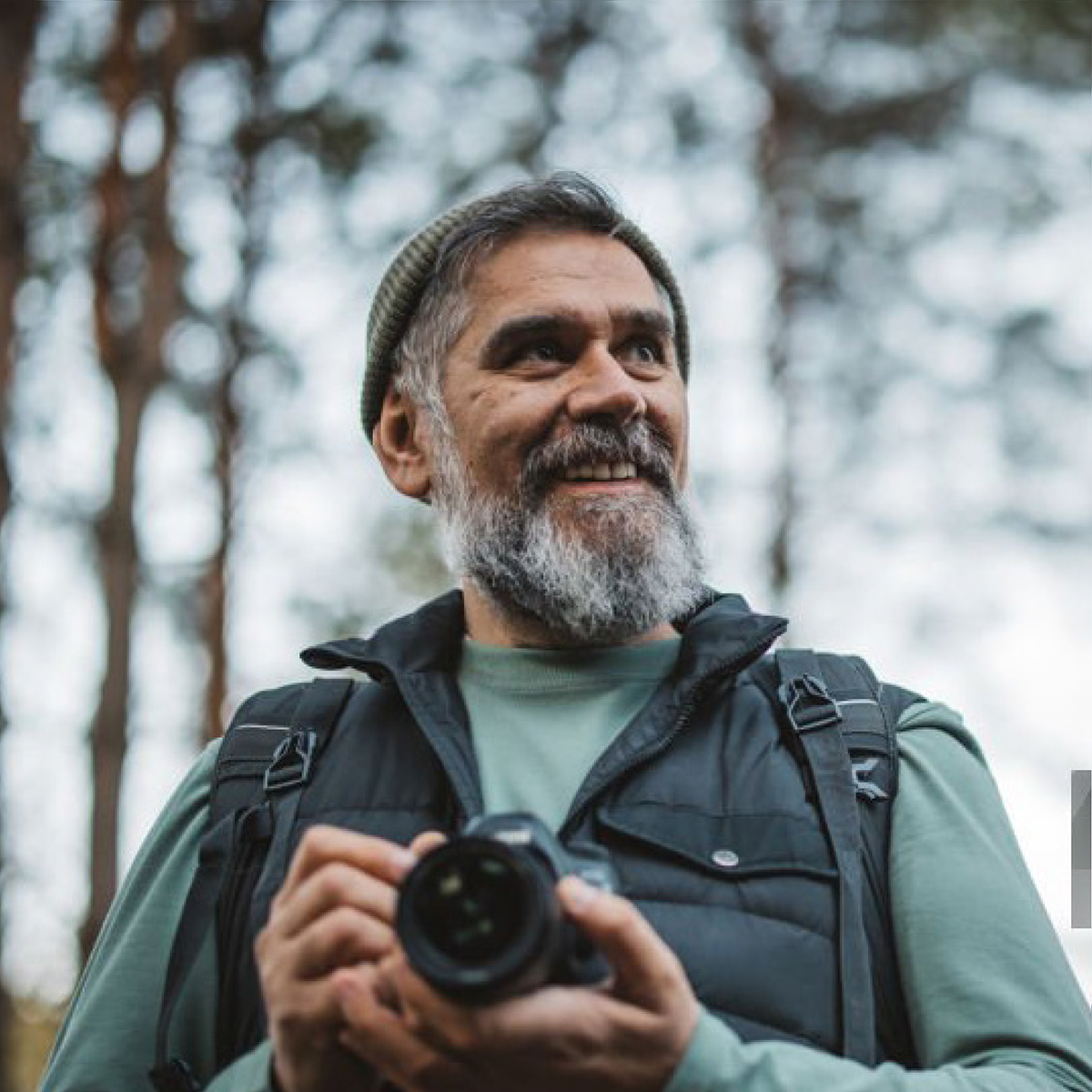 A professional portrait of a happy young adult man, showcasing confidence and positivity in a neutral setting.