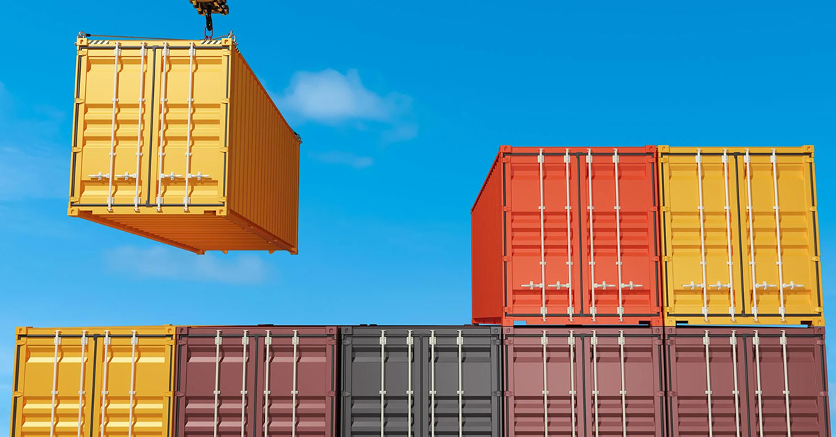 Stacked cargo containers on freight cars at a rail terminal, showing commercial shipping and freight transport operations.