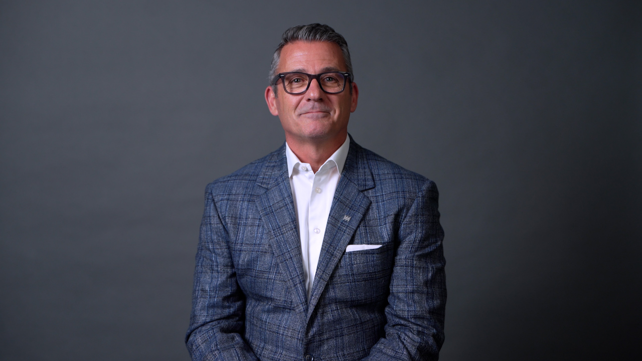 A professional portrait of a young adult businessman in a suit, exuding confidence and focus, isolated on a plain background.