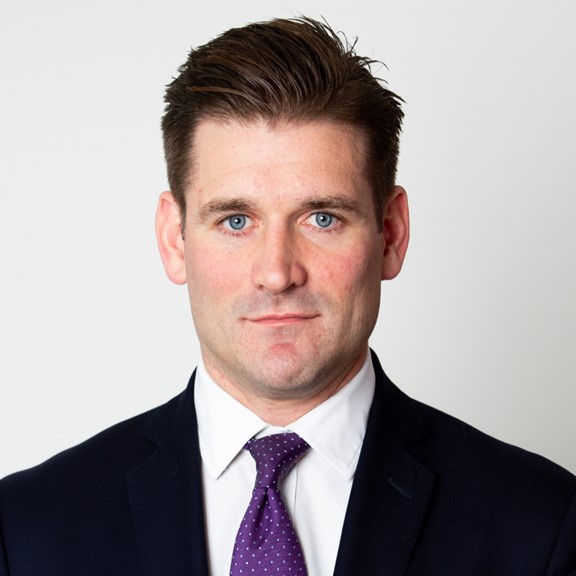 A professional portrait of a young adult businessman, isolated against a neutral background, exuding confidence and focus.