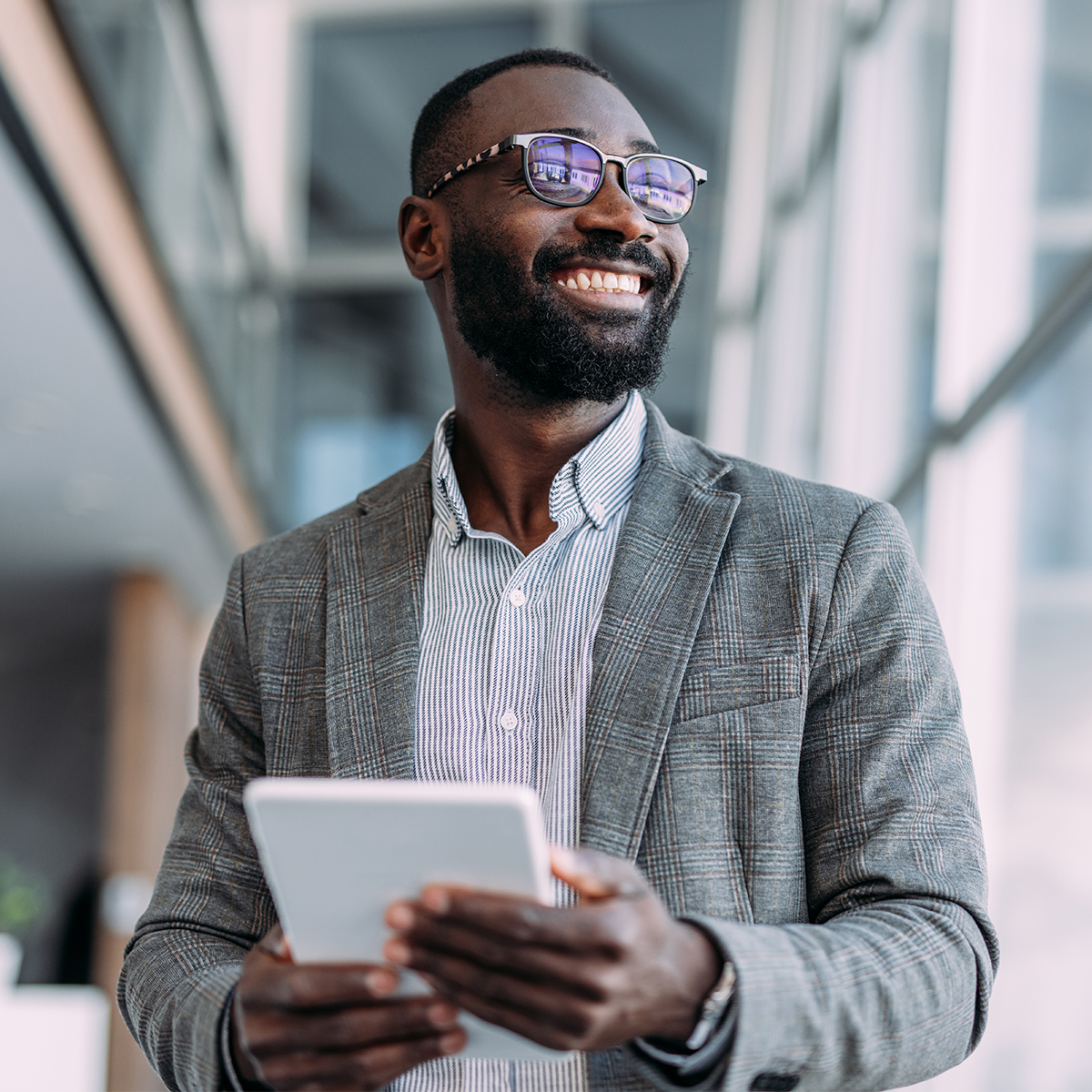 Smiling individual wearing glasses, looking off into the distance in a bright indoor space.