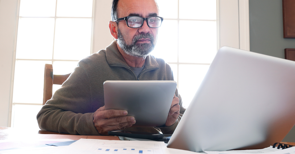 Un homme d'affaires joyeux utilise efficacement son ordinateur portable pour des activités basées sur Internet dans un cadre professionnel.