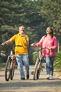 A woman and man laugh by their bicycles in a lifestyle portrait, portraying active, pedestrian-friendly urban exercise.