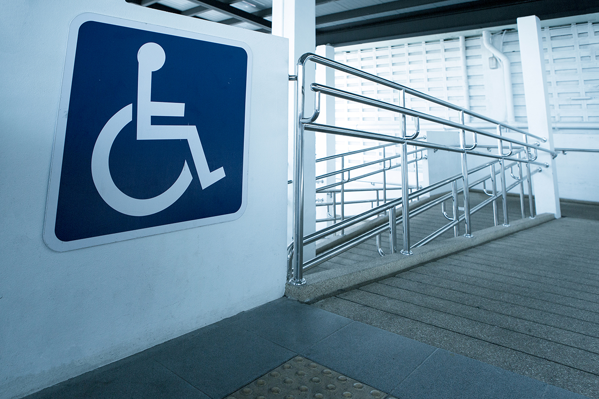 The business parking area features a prominent blue and white sign, symbolizing designated spaces for disabled or handicapped individuals.