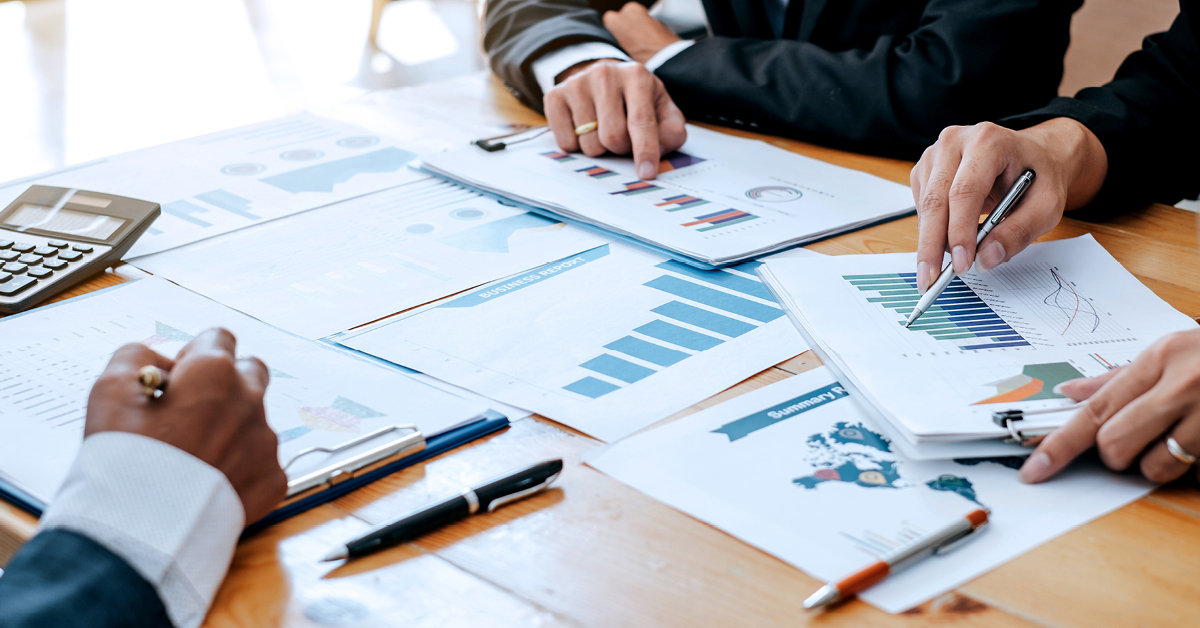 A businessman in an office setting meticulously manages financial documents, pen and paper in hand.
