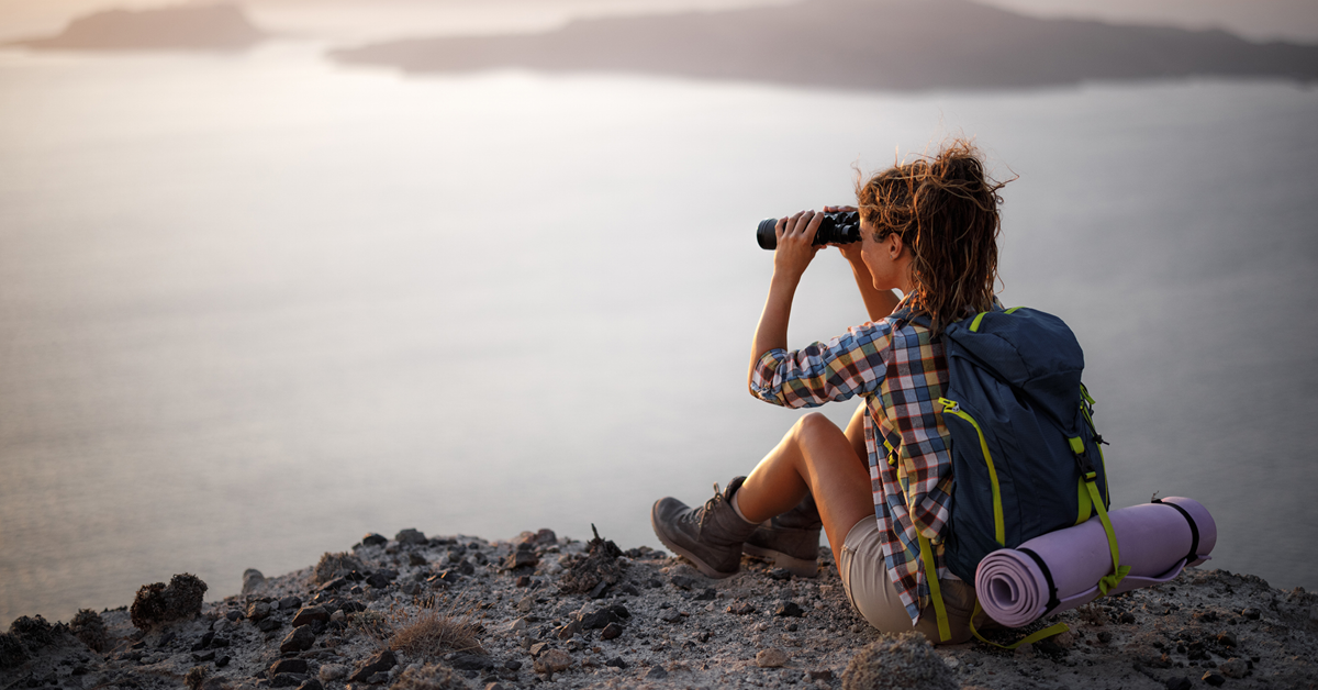 A young woman stands on a tranquil beach beneath an expansive sky, reflecting in a moment of peace and natural beauty.