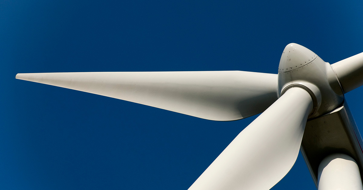 The white turbines under the blue sky symbolize wind energy power, with a flag highlighting electricity production.