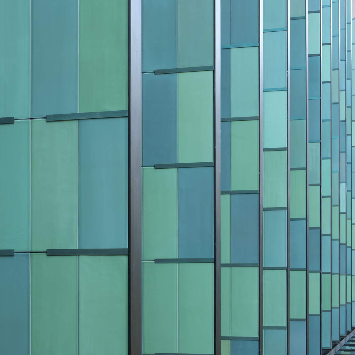Un bâtiment moderne en verre arbore un motif abstrait bleu sur ses fenêtres, offrant un cadre architectural élégant et contemporain.