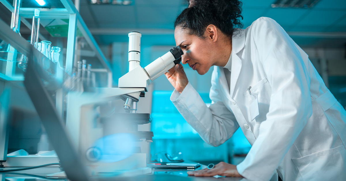 A proficient female scientist is conducting advanced medical research in a laboratory, utilizing chemistry and microscopes.