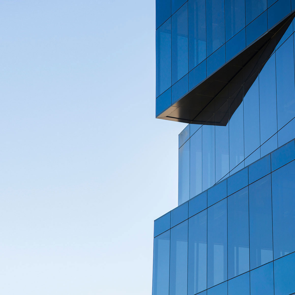 The modern glass office building reflects the blue sky, epitomizing urban business architecture in the city.