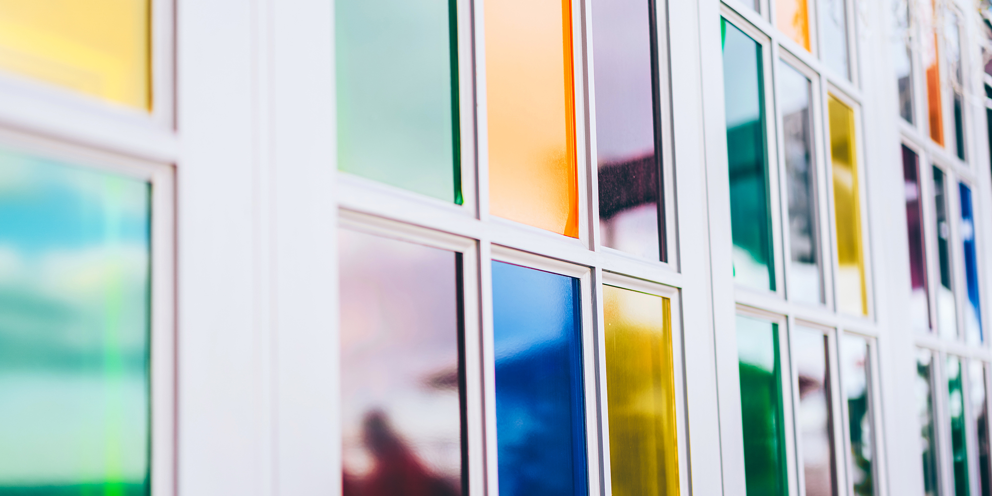 A vibrant blue door stands against a colorful background, with books neatly arranged on a shelf near a window, showcasing a modern design.
