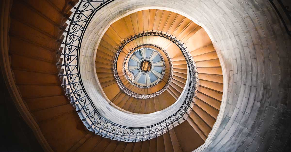 The interior architecture of this historic building features a circular dome, an old clock, and a spiral staircase.