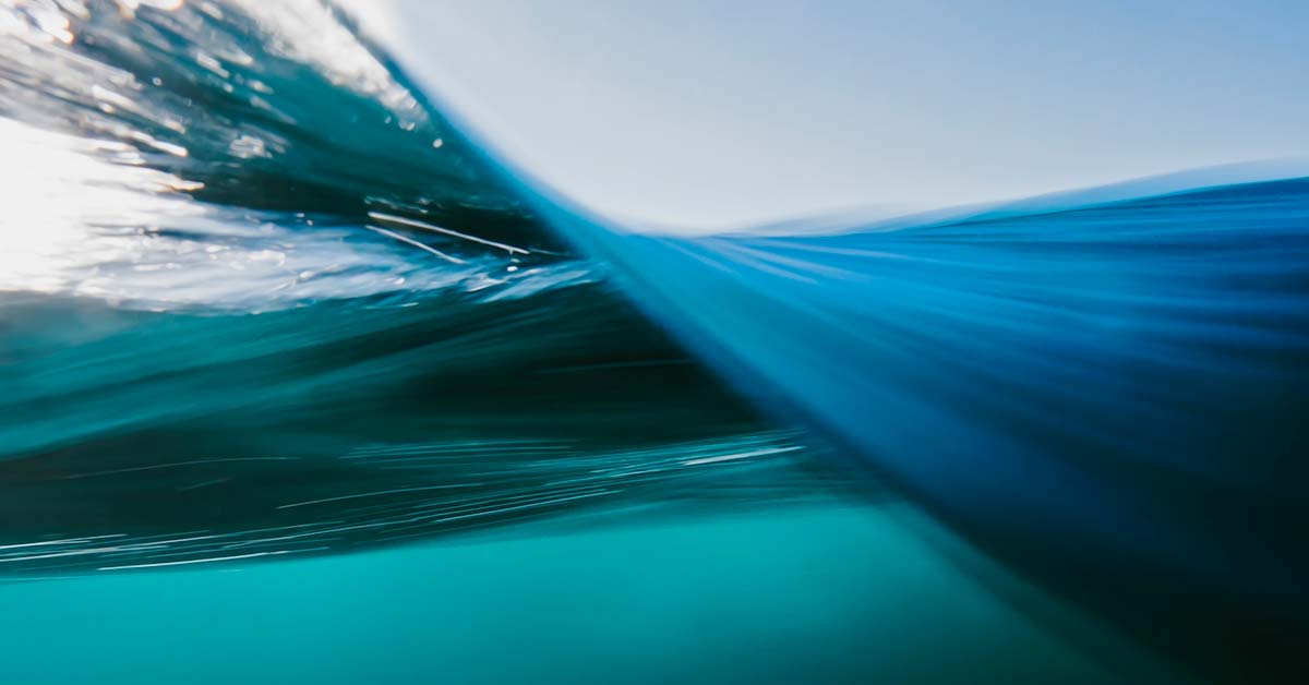 This abstract illustration presents a serene blue sky, ocean waves, and radiant light forming a professional water-themed background.
