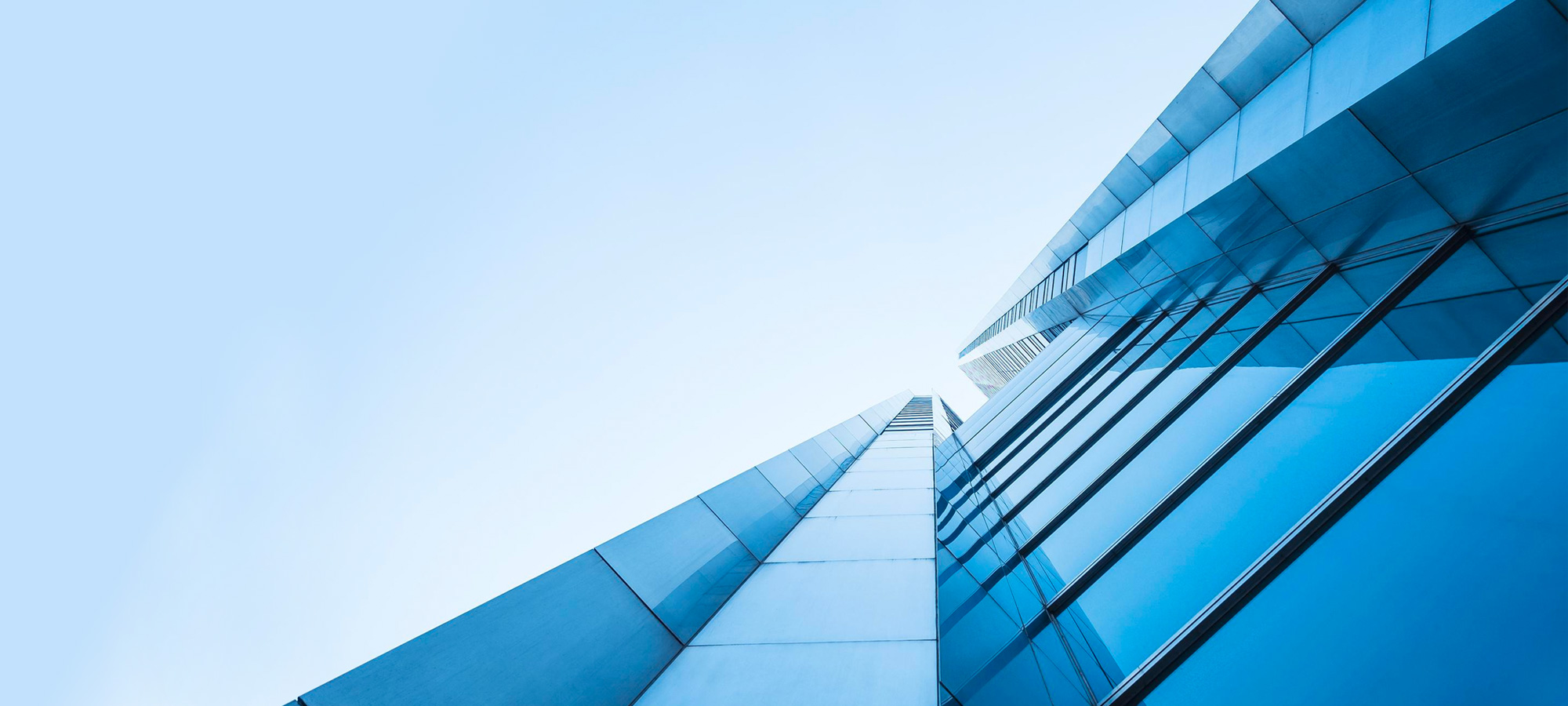 The modern glass building, with its abstract architecture, stands tall against a blue sky backdrop in the bustling city.