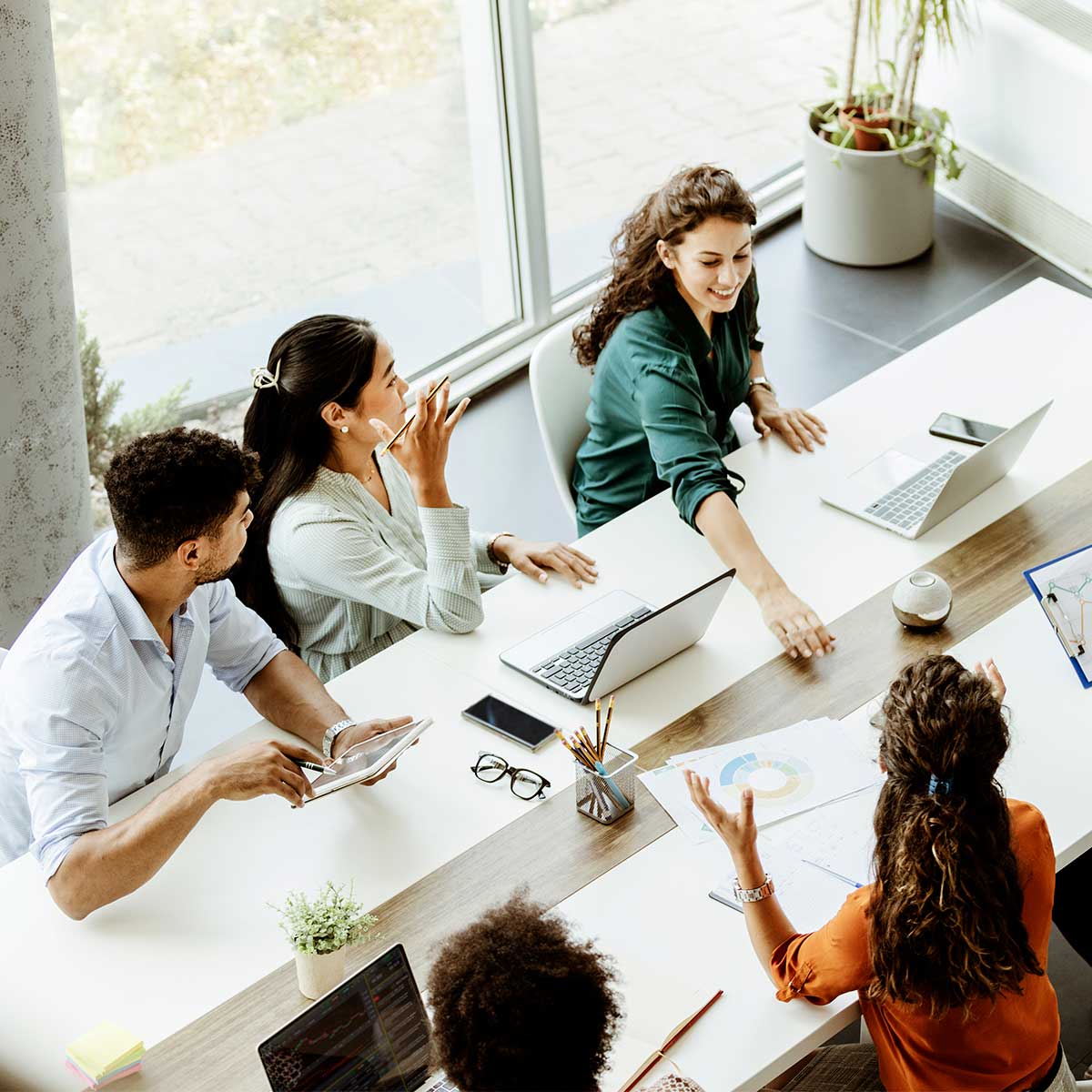 A businesswoman collaborates with her team during a meeting in their modern office setting.