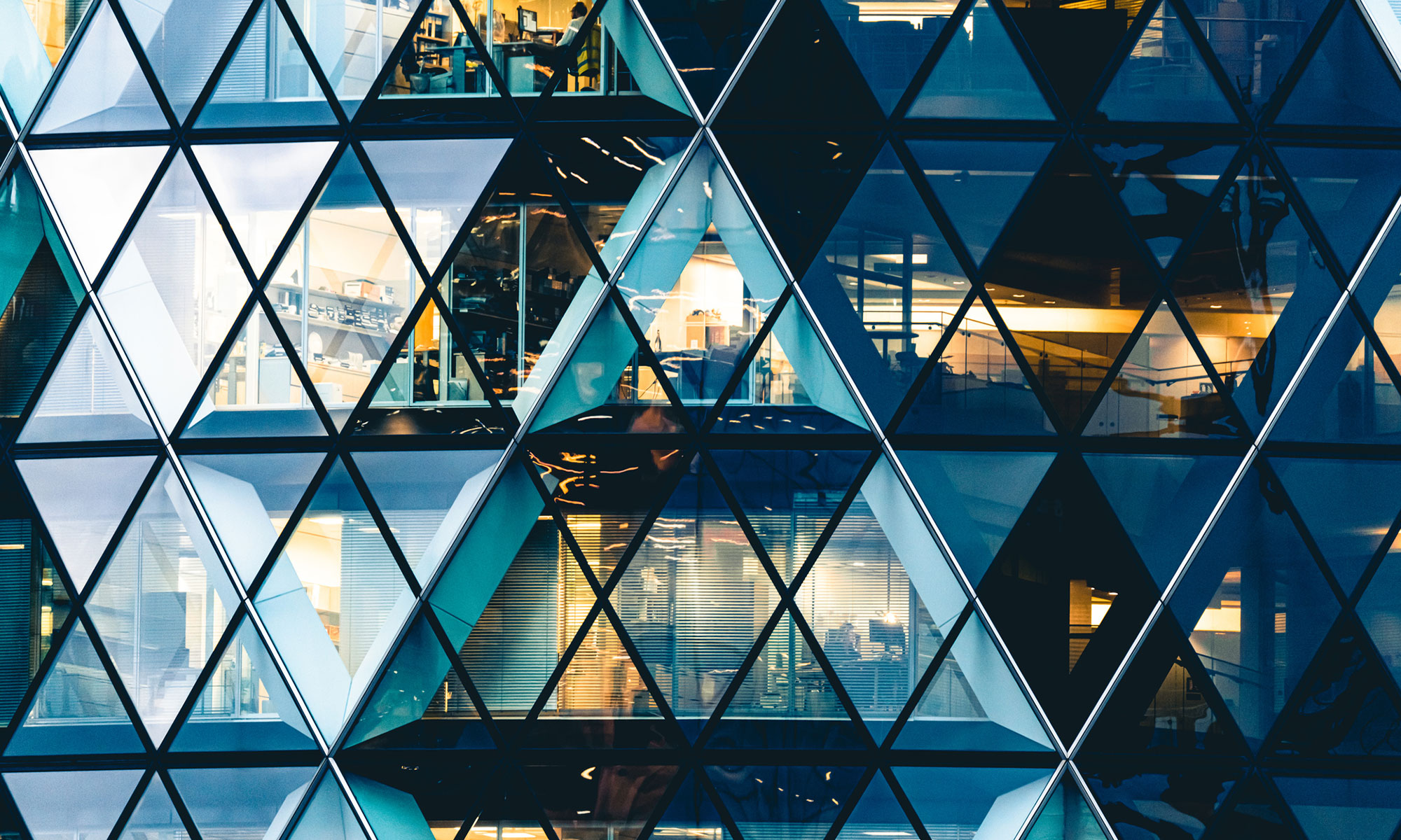 Symmetrical architectural photograph of a triangular stained glass structure with patterned vertices and networked design.