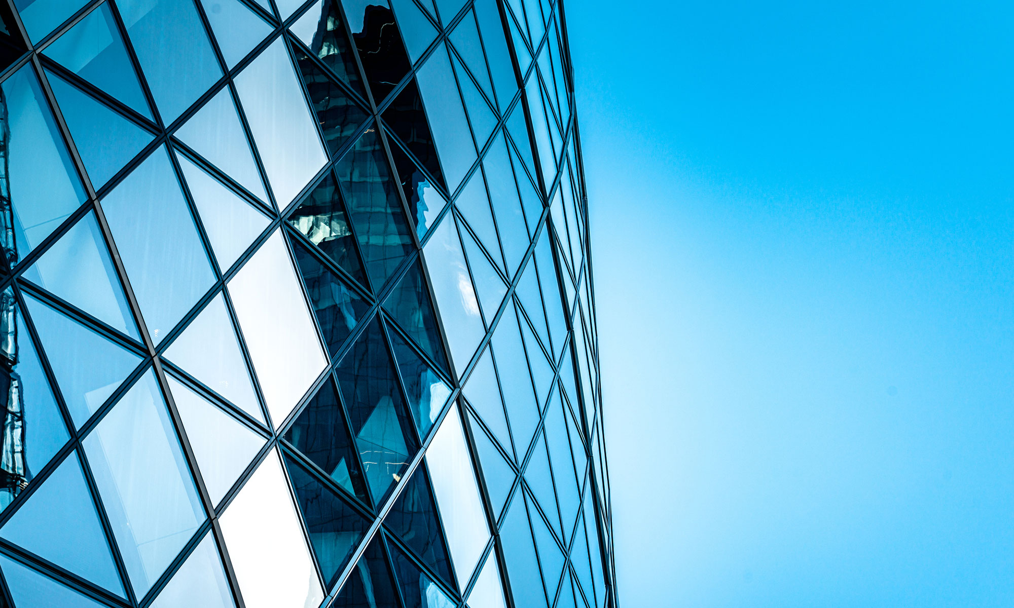 Architectural photograph of a modern office tower with a triangular-patterned facade set against an abstract landscape.