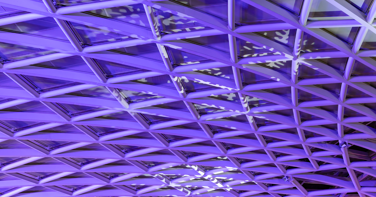Abstract architectural photograph of an atrium roof canopy with patterned structural lines converging to a central vertex.