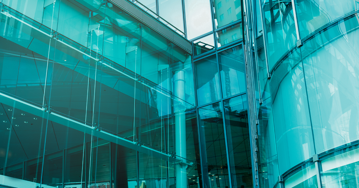 Modern corporate office with cylindrical facade, tinted-glass atrium, revolving door, and neatly landscaped grounds.