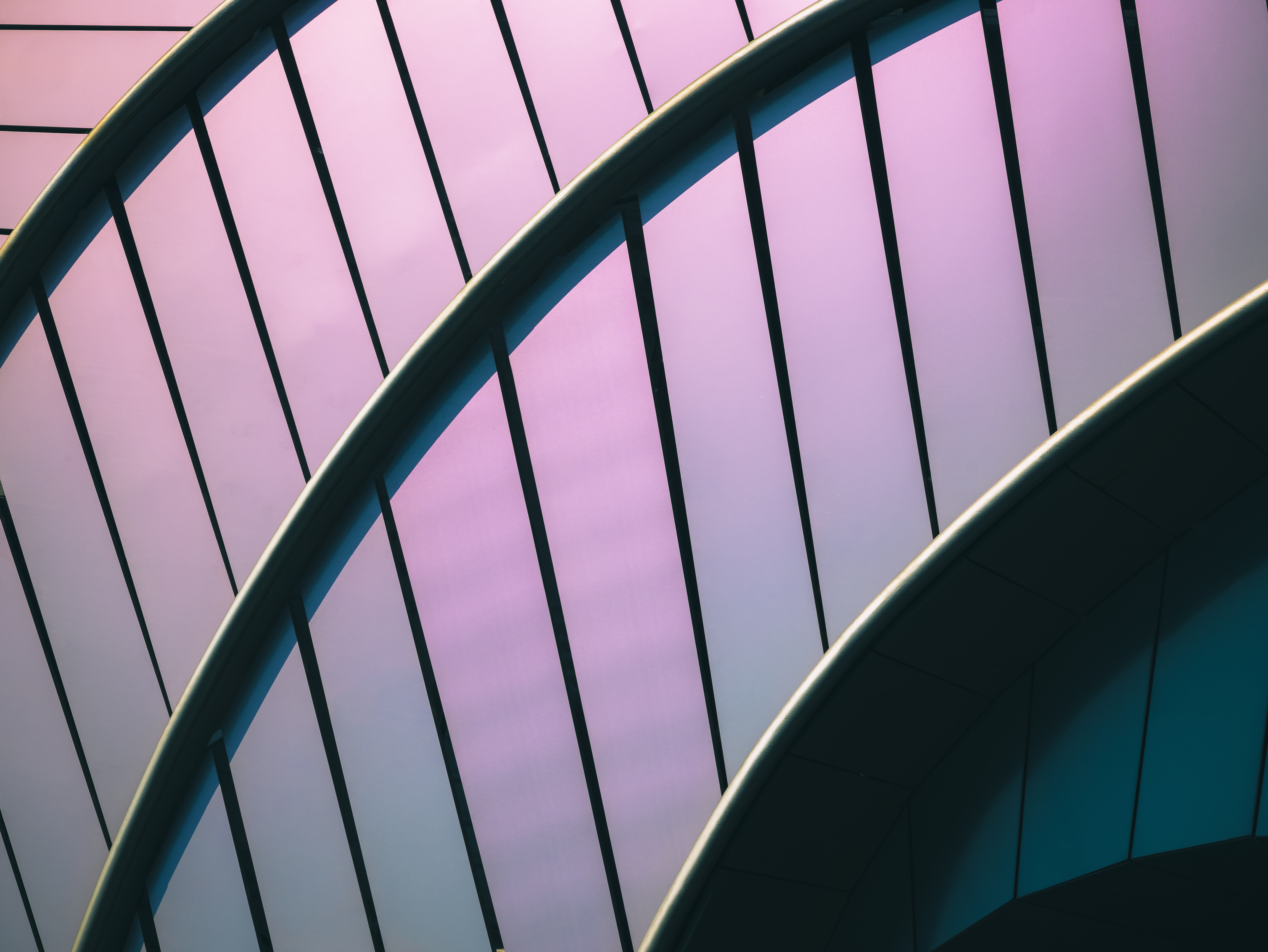 Abstract architectural photograph showing a patterned facade and awning, with a structured metal railing in the foreground.