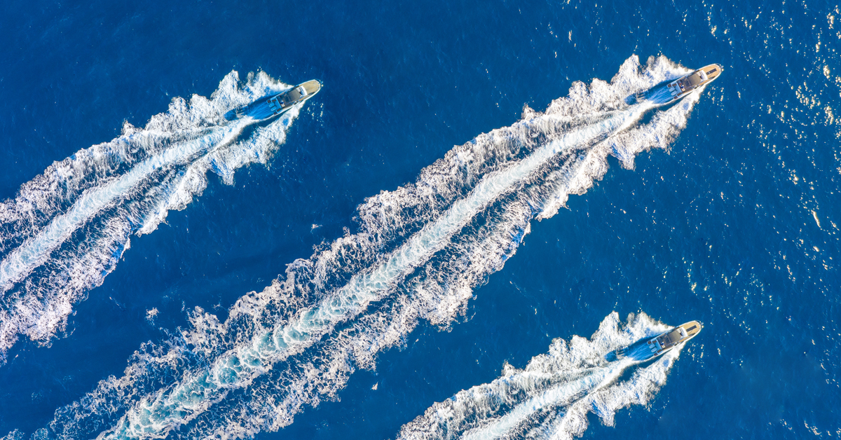 Image of three boats jetting through the ocean, with the center boat slightly in front of the others