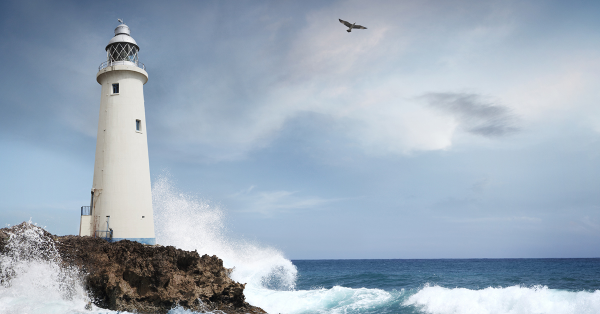 Un phare sur un littoral rocheux, avec des vagues et un ciel nuageux.