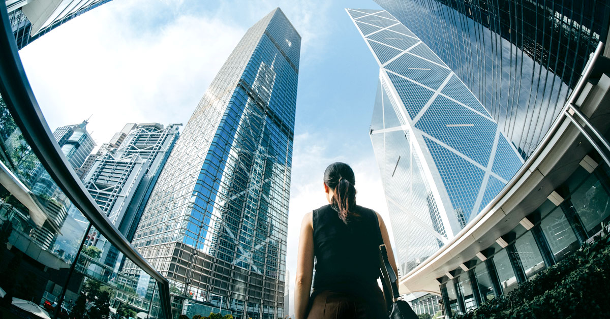 woman looking into large buildings in a financial district of a major city