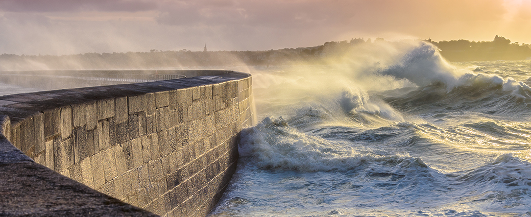 Image of stormy seas battering a harbour wall