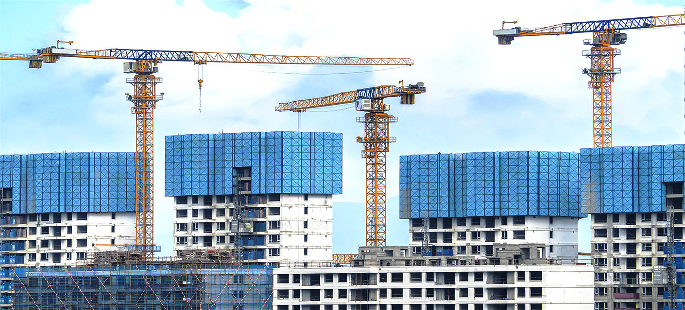 Image of a skysraper  in the beginning stages of being built by three cranes