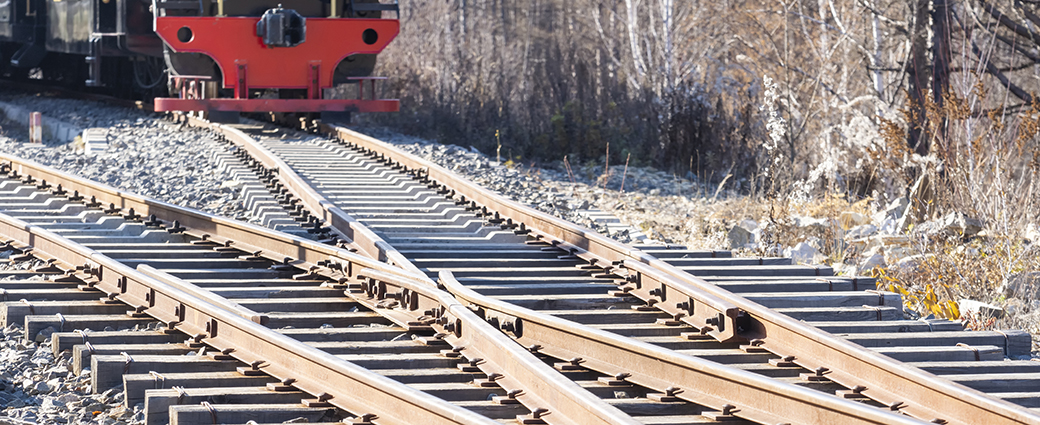 Zoomed in mage of intersecting railroads, with a train approaching in the background