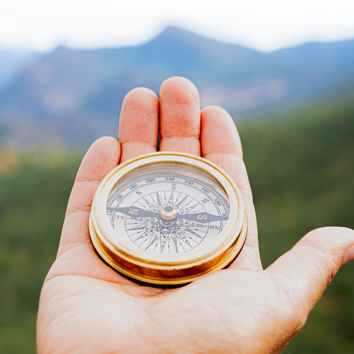 Square display of miniature hiking gear with compass, GPS, stopwatch, medal, and balm for adventure travel photography.
