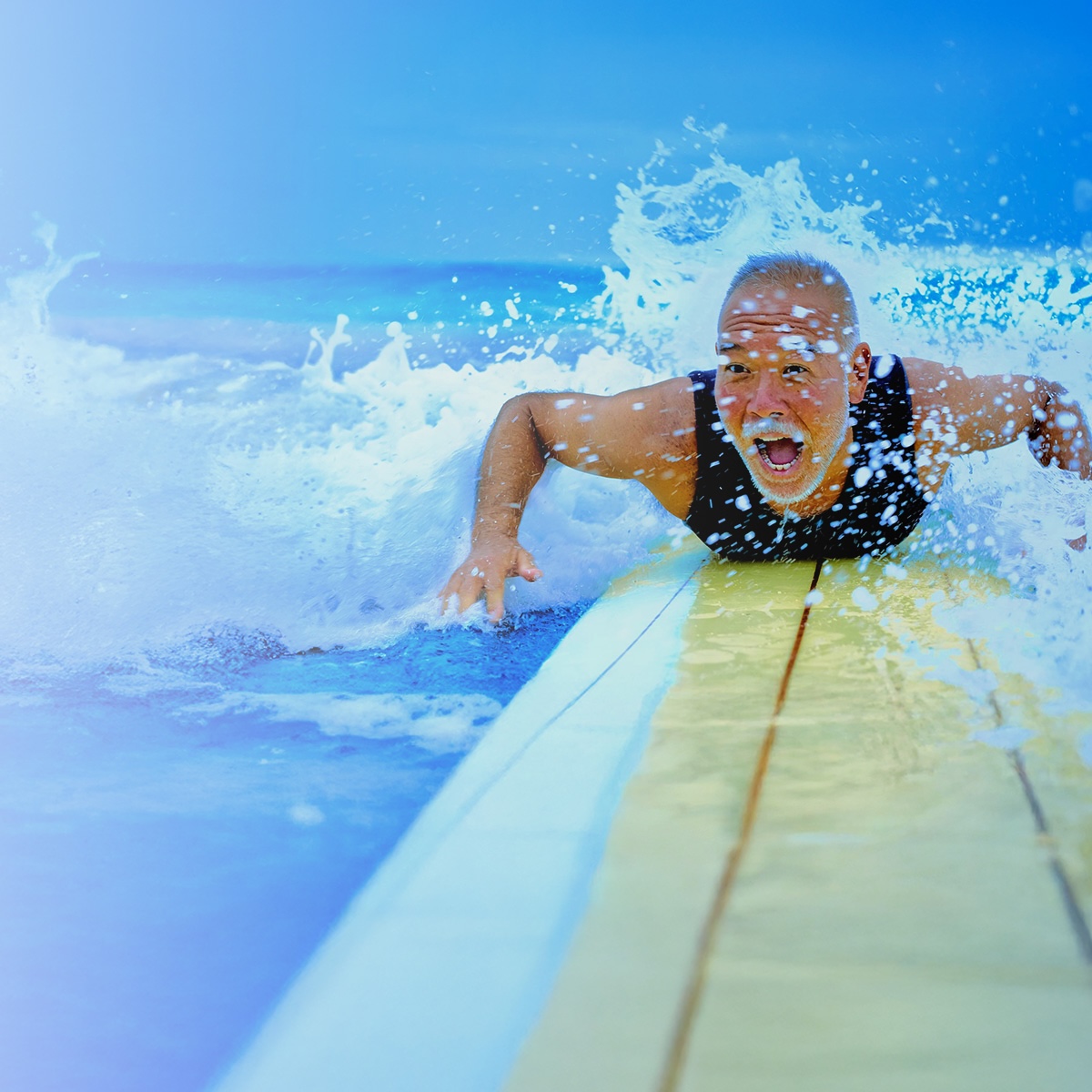 An older man surfs in the ocean