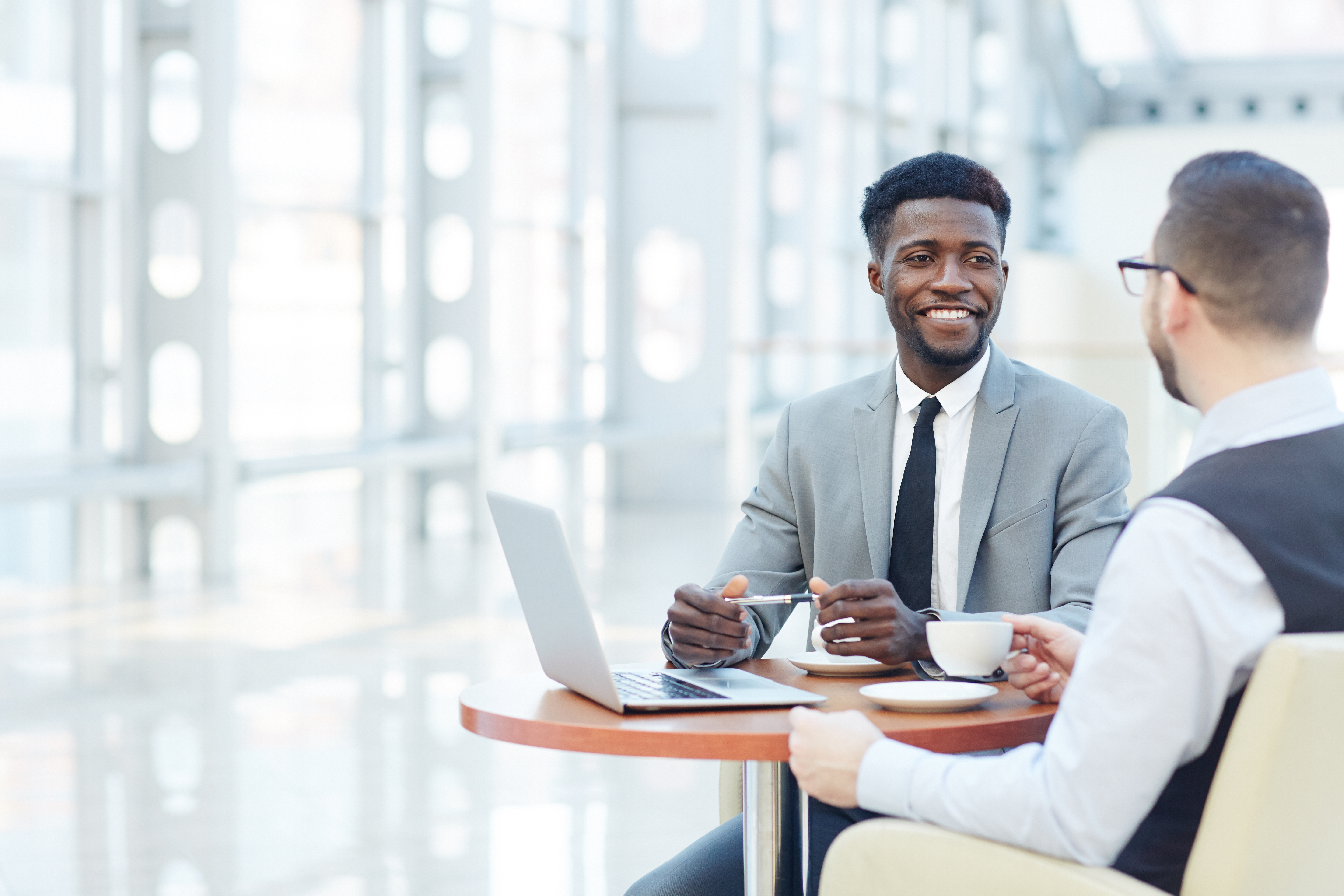 A cheerful businesswoman and businessman are collaboratively working in a bustling office environment.